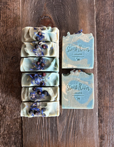 Image shows a green, blue and white soap with botanicals on top