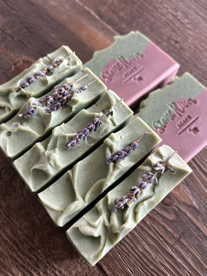 Image shows a group of purple and green soaps with lavender sprigs on top.