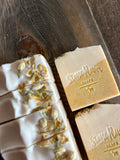 Image shows a group of white and yellow soaps with jasmine buds on top