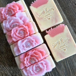 Image shows a group of white and pink soaps with pink glycerin soaps on top