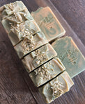 Image shows a group of yellow and green soaps topped with yellow flower petals.
