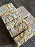 Image shows a group of tan soaps with gold mica swirls on top
