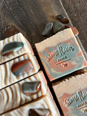 Image shows a group of orange, green, and tan soaps with real stones on top