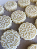 Image shows unpackaged lotion bars with designs on the tops.