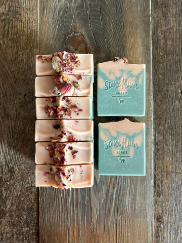 Image shows a group of light pink and soft green soaps topped with rose petals.