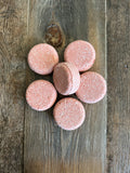 Image shows pink circle shaped shampoo bars