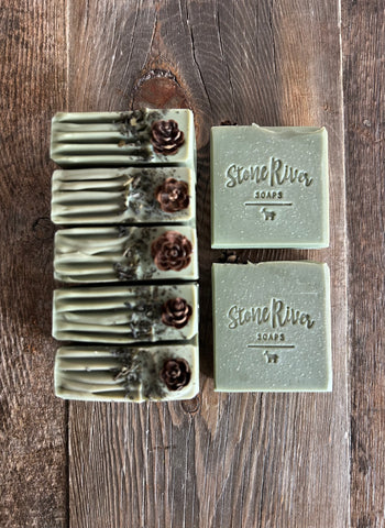 Image shows a group of green soaps with hemlock cones and green tea leaves on top.