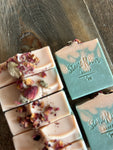 Image shows a group of light pink and soft green soaps topped with rose petals.