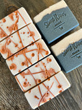 Image shows a group of black and white soaps with copper dots and swirls on top