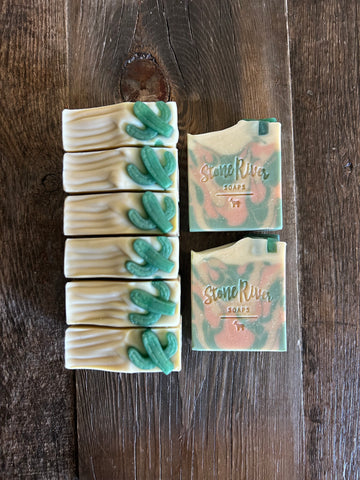 Image shows a group of peach, green, and white soaps with green cactus soaps on top.