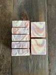 Image shows a group of pink, purple, and white soaps with a swirl design.