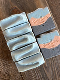 Image shows a group of black, orange, and blue soaps with loofah shreds inside.