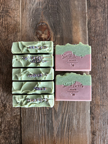 Image shows a group of purple and green soaps with lavender sprigs on top.