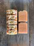Image shows a group of peach colored soaps with jasmine buds on top