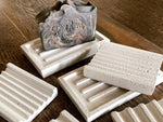 Shows a variety of white soap dishes with a soap on one.